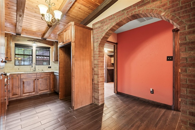7220 Amy St, Dallas, TX 75217 - kitchen featuring a chandelier, dark wood finished floors, beam ceiling, a sink, and brick wall