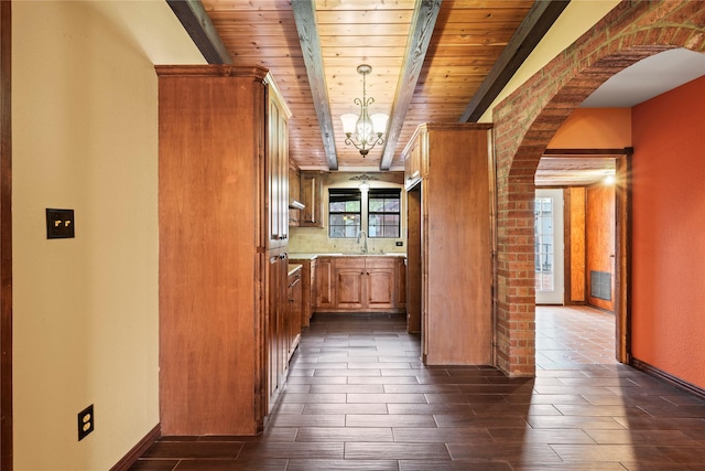 7220 Amy St, Dallas, TX 75217 - kitchen with light countertops, a sink, arched walkways, beamed ceiling, and brown cabinets