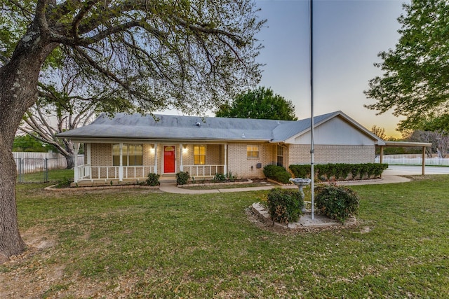 ranch-style home with a porch, fence, a front lawn, and brick siding