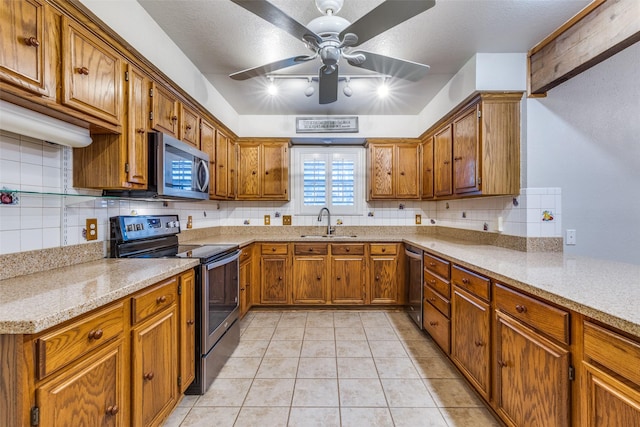 kitchen with brown cabinets, appliances with stainless steel finishes, decorative backsplash, and a sink