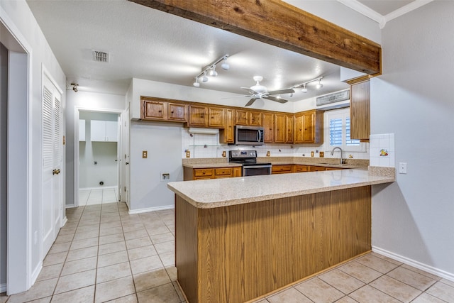 kitchen featuring a peninsula, light tile patterned floors, light countertops, brown cabinets, and stainless steel appliances