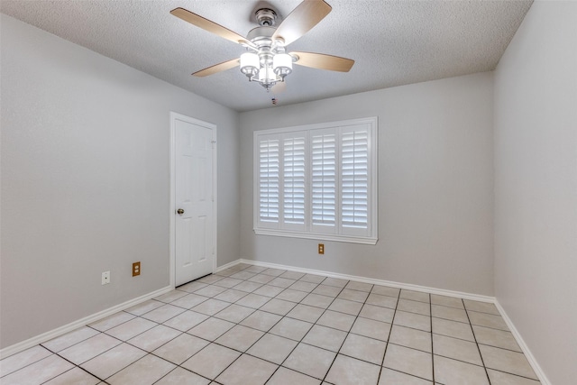 empty room with light tile patterned floors, ceiling fan, baseboards, and a textured ceiling