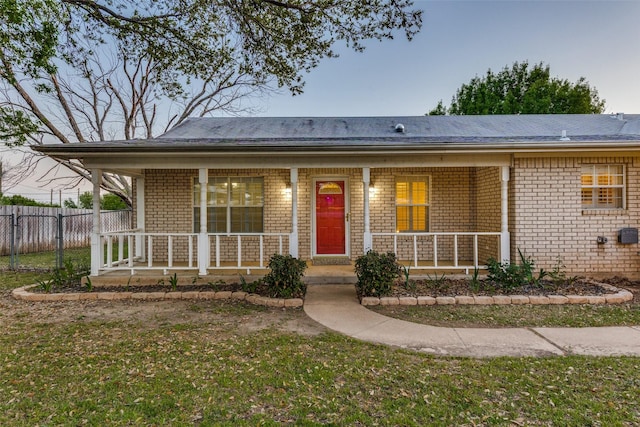 ranch-style home with brick siding, fence, and covered porch