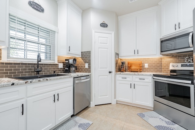 kitchen featuring light tile patterned flooring, white cabinetry, a sink, and appliances with stainless steel finishes