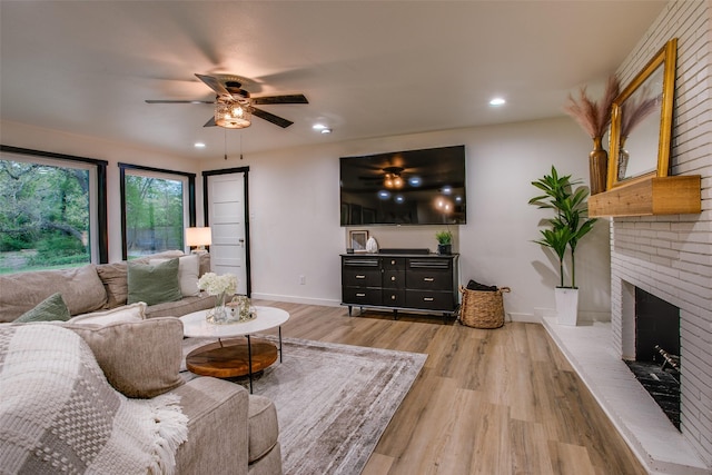 living room featuring wood finished floors, a brick fireplace, baseboards, ceiling fan, and recessed lighting
