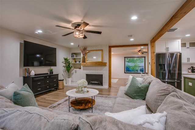 living area featuring visible vents, a ceiling fan, and light wood finished floors