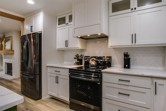 kitchen with light stone counters, white cabinets, light wood-type flooring, custom exhaust hood, and black appliances