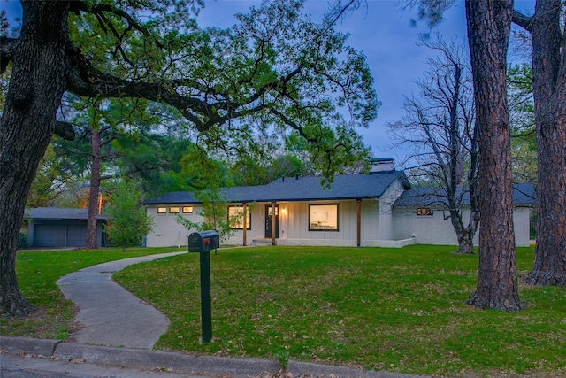 view of front facade with board and batten siding, a front yard, and a garage