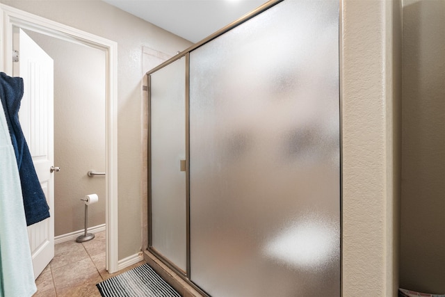 bathroom with a stall shower and tile patterned floors