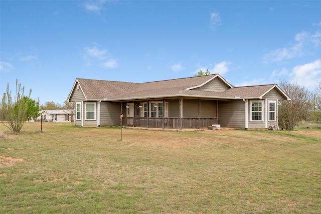 ranch-style house featuring covered porch, roof with shingles, and a front lawn