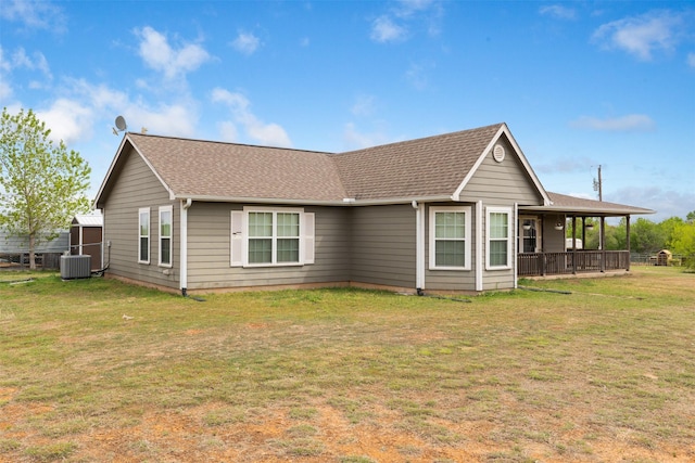 view of front of home with central air condition unit, a front lawn, and roof with shingles
