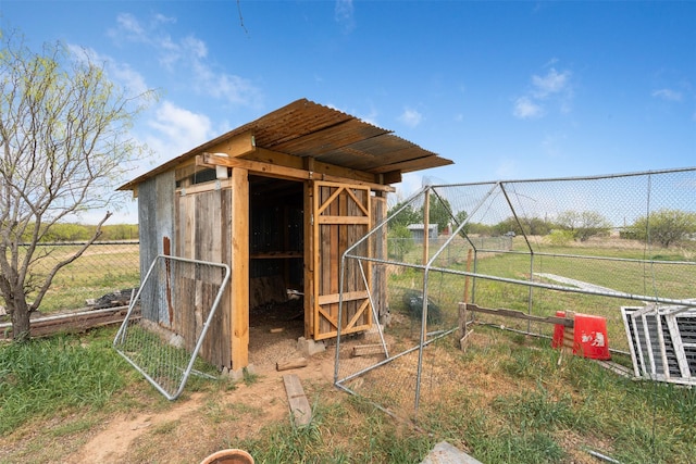 view of outbuilding featuring fence, an outdoor structure, and a rural view