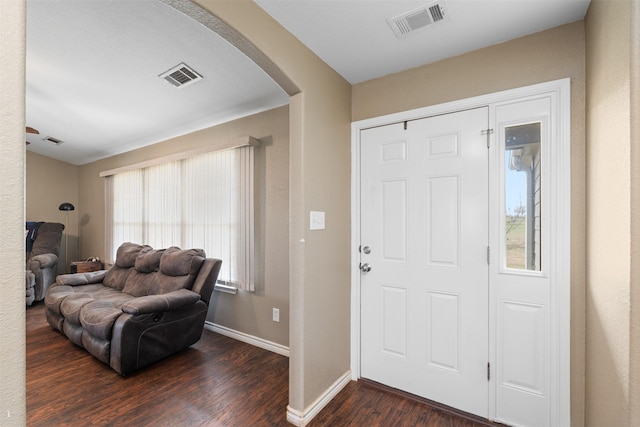 foyer entrance with arched walkways, dark wood-style flooring, visible vents, and baseboards