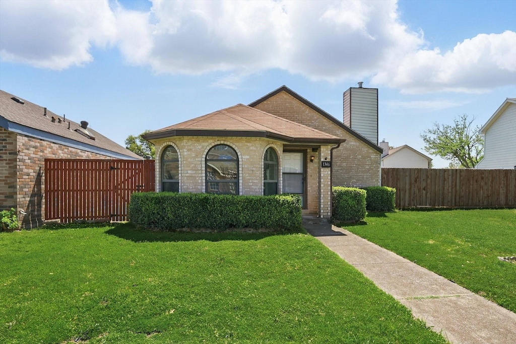 1346 Maplewood Dr, Lewisville, TX 75067 - view of front of house featuring a chimney, brick siding, fence, and a front lawn