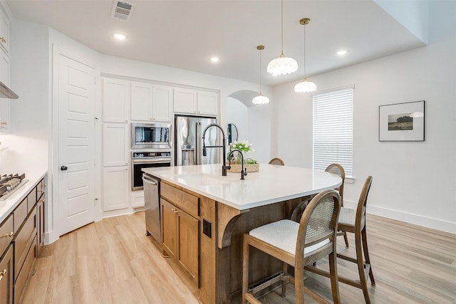 1512 Trailblazer Way, Northlake, TX 76247 - kitchen with stainless steel appliances, a breakfast bar, light wood finished floors, arched walkways, and recessed lighting