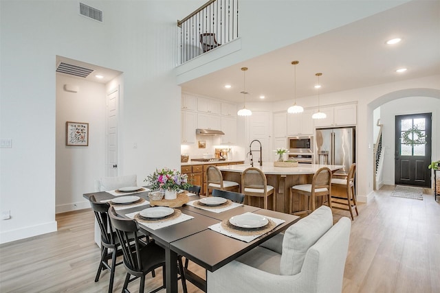 1512 Trailblazer Way, Northlake, TX 76247 - dining area featuring arched walkways, baseboards, light wood-style floors, recessed lighting, and a high ceiling