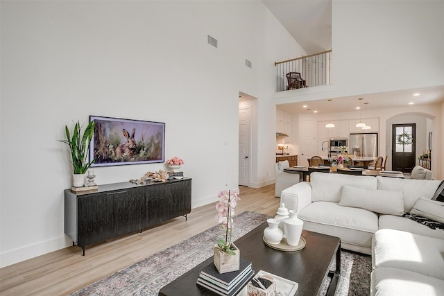 1512 Trailblazer Way, Northlake, TX 76247 - living room featuring light wood-type flooring, baseboards, arched walkways, and a high ceiling