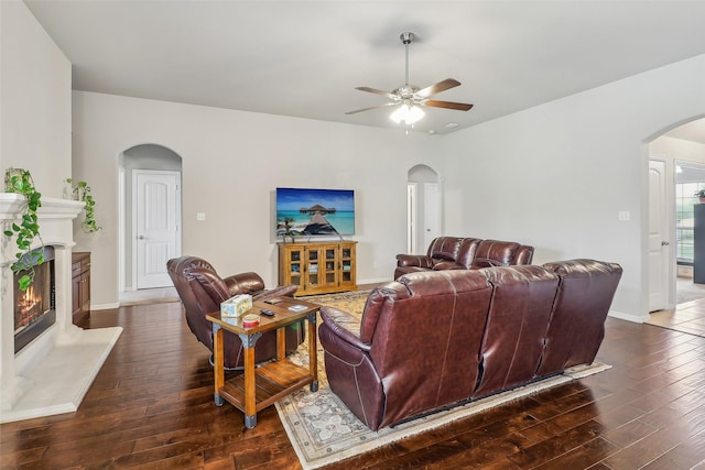 7203 Veal Station Rd, Weatherford, TX 76085 - living room with arched walkways, dark wood-style floors, a glass covered fireplace, and a ceiling fan