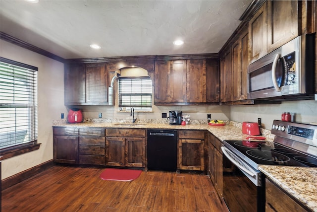 kitchen with light stone counters, a sink, appliances with stainless steel finishes, dark wood-style floors, and dark brown cabinets