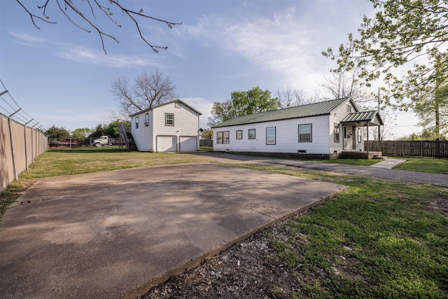 view of front of property with metal roof, fence, a front yard, and a garage