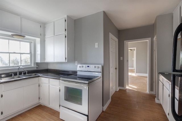 kitchen with dark countertops, white cabinetry, a sink, light wood-style floors, and electric range