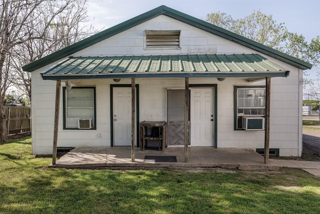 view of front of property with a front lawn, metal roof, fence, and a patio