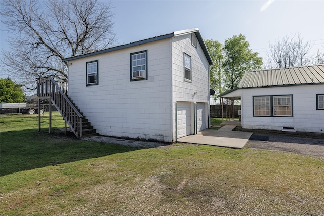 view of property exterior with metal roof, a garage, stairway, driveway, and a yard