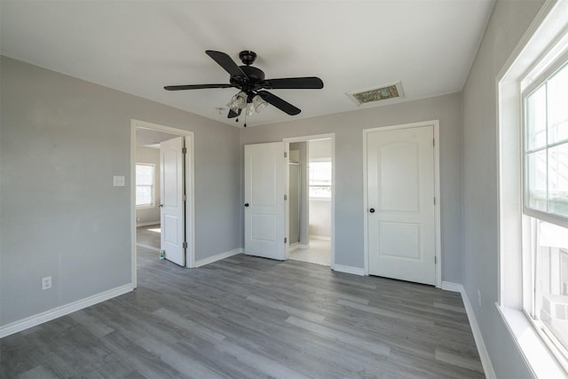 unfurnished bedroom with wood finished floors, baseboards, ceiling fan, and visible vents