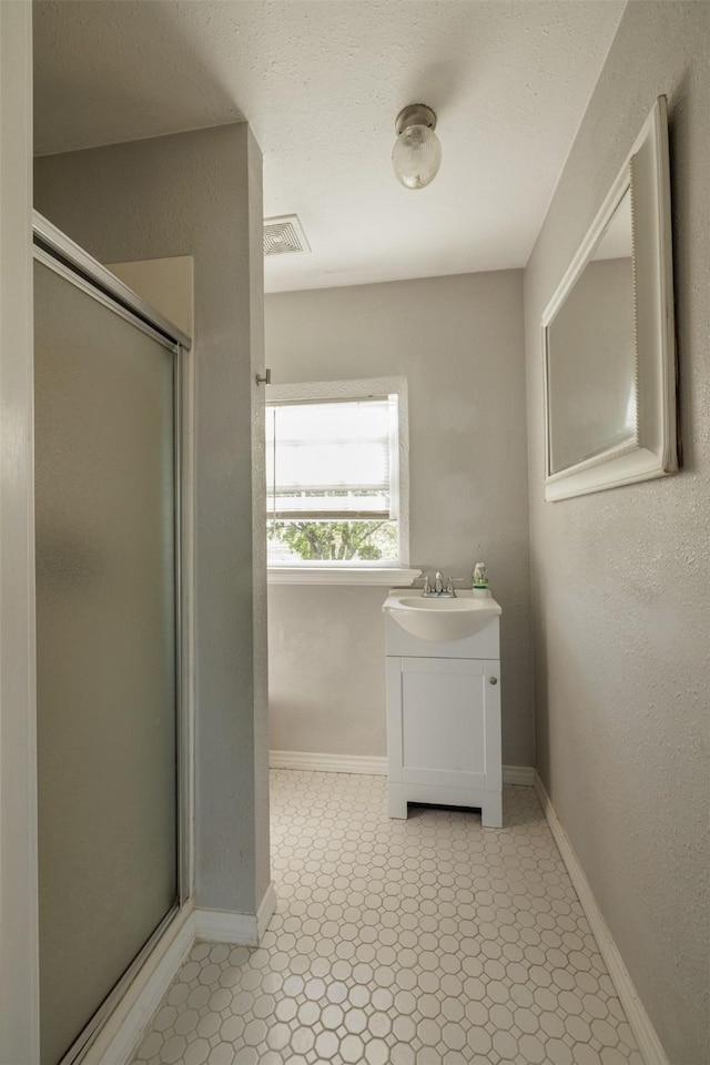 full bath featuring vanity, a shower stall, baseboards, and visible vents