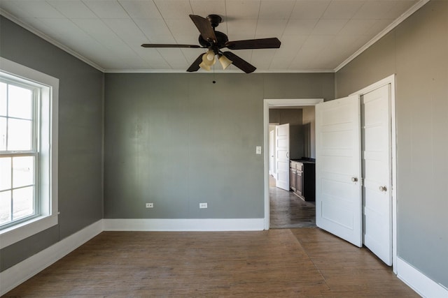 unfurnished room featuring baseboards, dark wood-style floors, crown molding, and a ceiling fan