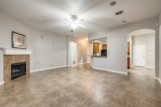 9212 Water Oak Dr, Arlington, TX 76002 - unfurnished living room with arched walkways, a ceiling fan, a tiled fireplace, and baseboards