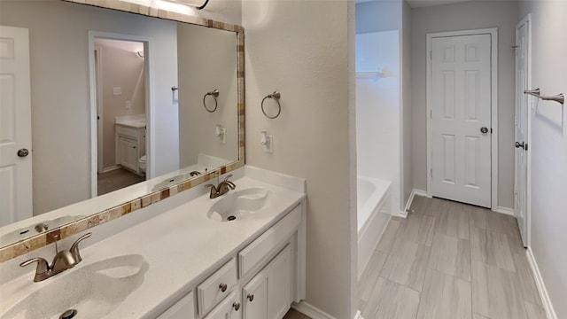 bathroom featuring double vanity, toilet, and a sink