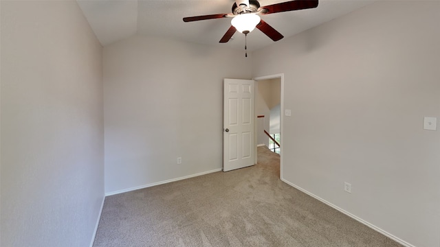 spare room featuring a ceiling fan, lofted ceiling, baseboards, and light colored carpet