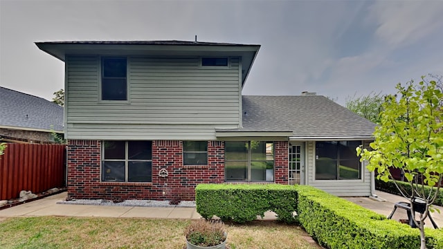 rear view of property with a patio area, a shingled roof, fence, and brick siding