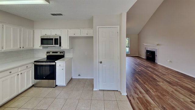 kitchen with white cabinets, light countertops, decorative backsplash, and stainless steel appliances