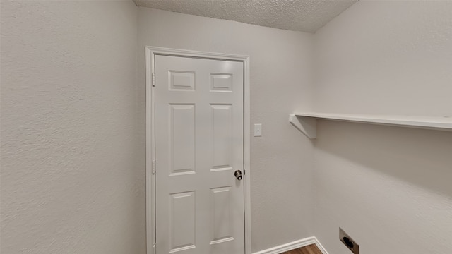 washroom featuring a textured ceiling, laundry area, a textured wall, and electric dryer hookup
