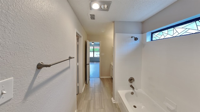 bathroom featuring a healthy amount of sunlight, a textured ceiling, bathtub / shower combination, and visible vents