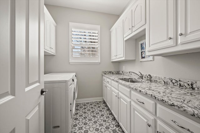 washroom with washing machine and clothes dryer, cabinet space, a sink, and baseboards