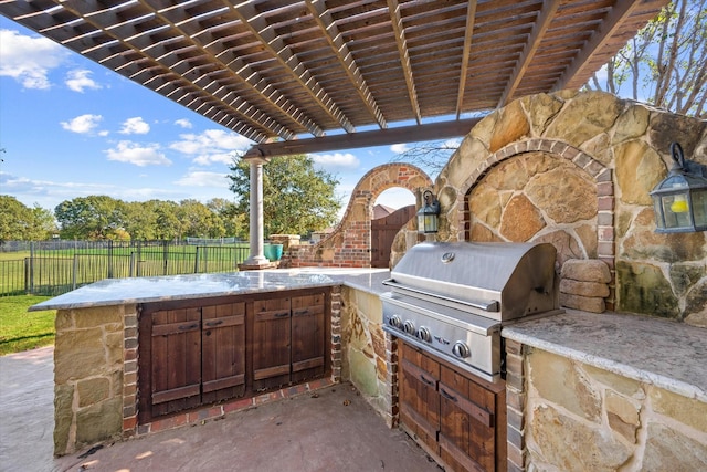view of patio / terrace featuring fence, exterior kitchen, grilling area, and a pergola