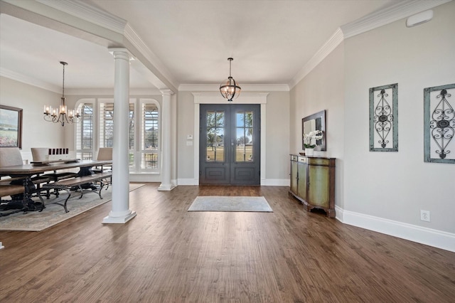 entryway with crown molding, dark wood-style floors, baseboards, ornate columns, and an inviting chandelier