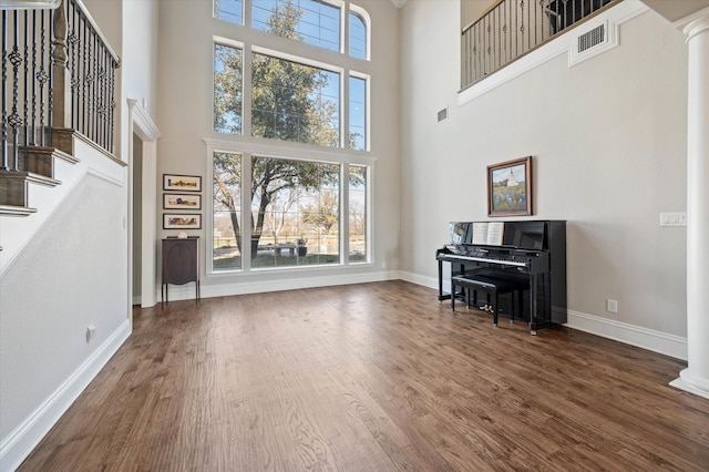 living room with ornate columns, stairs, dark wood-style floors, and baseboards