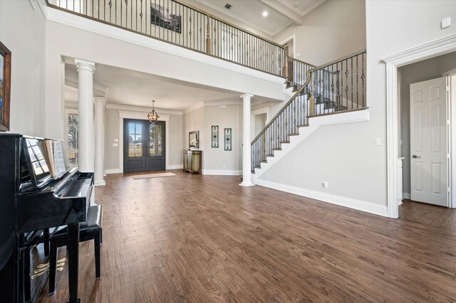 interior space featuring ornate columns, dark wood-style floors, and a high ceiling
