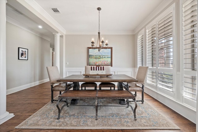 dining area with decorative columns, wood finished floors, visible vents, ornamental molding, and an inviting chandelier