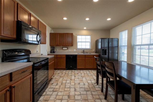 kitchen with black appliances, light countertops, recessed lighting, and brown cabinetry