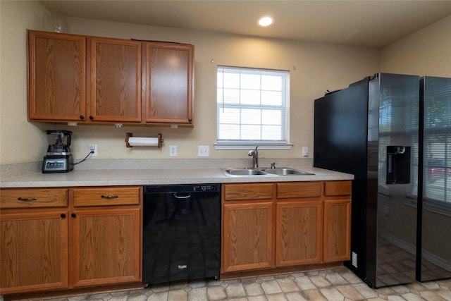 kitchen featuring light countertops, a sink, brown cabinetry, black appliances, and recessed lighting