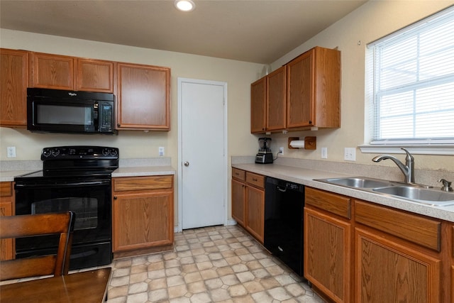 kitchen featuring a sink, light countertops, black appliances, and brown cabinetry