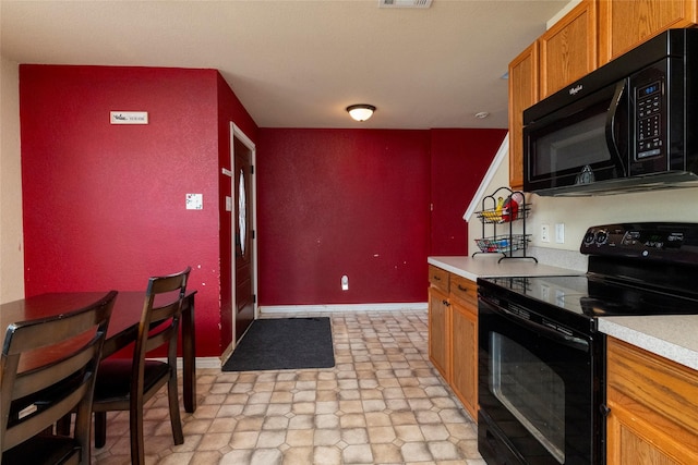 kitchen featuring baseboards, black appliances, light countertops, and brown cabinetry