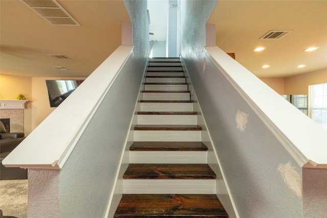 stairway featuring recessed lighting, a fireplace, and visible vents