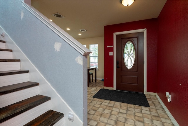 foyer entrance featuring baseboards, visible vents, and stairway