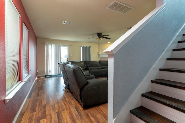 living area featuring stairs, visible vents, a ceiling fan, and wood finished floors